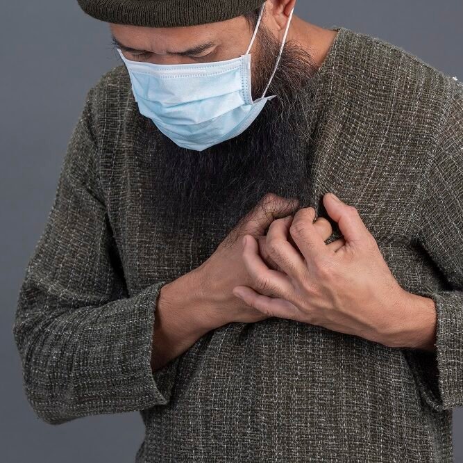 Older man wearing a mask and holding his chest in discomfort, symbolizing symptoms needing Atrial Fibrillation Treatment in Indore by Dr. Akhilesh Jain.