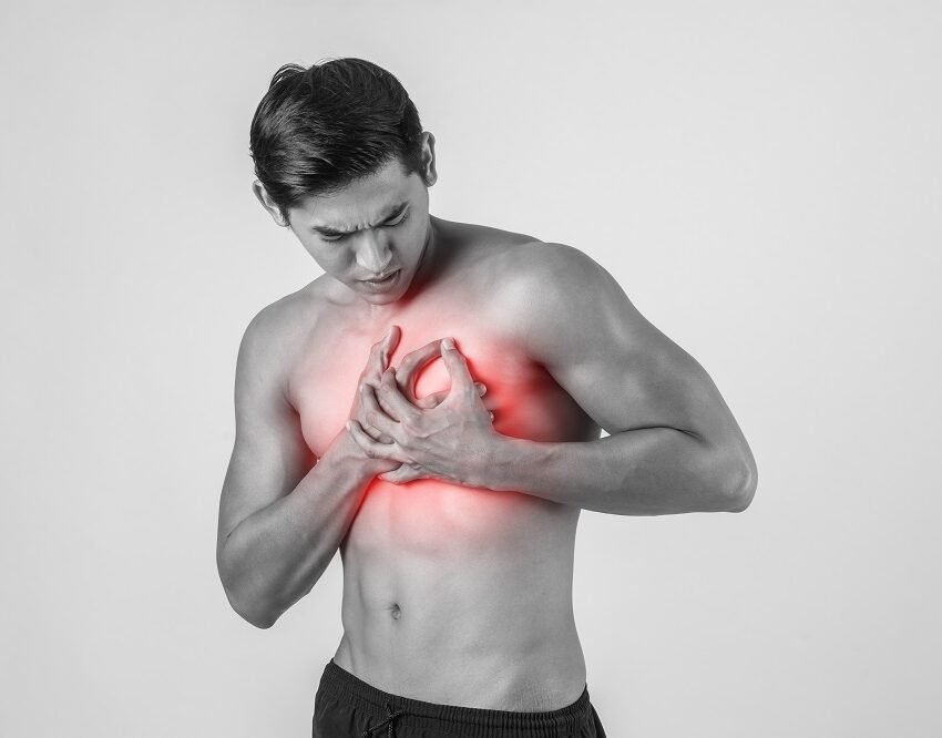 Young man grasping his chest with visible discomfort, highlighting the urgency of Arrhythmia Treatment in Indore by Dr. Akhilesh Jain.
